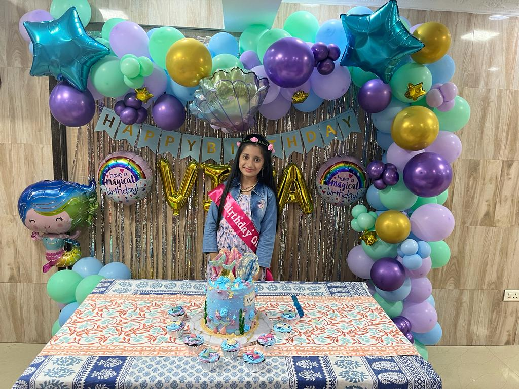 Colorful birthday party with pastel balloon arch and cake